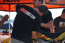 A pit crew member from Team Malcolm Smith/Norco Tires works on one of the motorcycles.