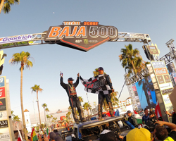 Bryce Menzie and co-pilot Pete stand atop the Red Bull sponsored Trophy Truck and celebrate their third Baja 500 overall victory