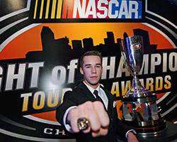 2014 NASCAR K&N Pro Series East champion Ben Rhodes poses in front of the championship trophy