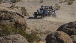 Shot of Jordan Pellegrino coming out of a rock trail and heading toward the open desert